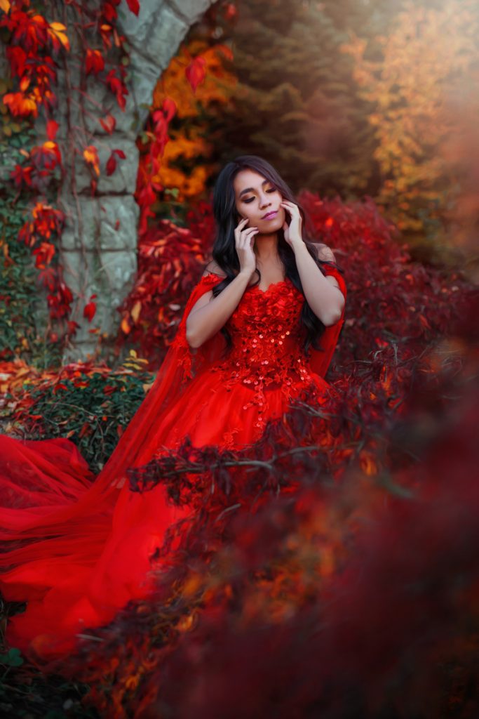 Herbst Fotoshooting in Luzern: Model in rotem Kleid vor goldenem Herbstlaub, natürliche Pose im warmen Sonnenlicht – klassische Herbststimmung mit Autumn Colors