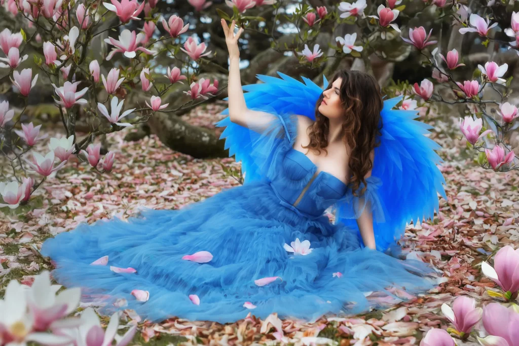 Verträumte-und-sinnliche-Szene-mit-Frau-im-blauen-Kleid-und-Engelsflügeln-umgeben-von-Magnolien