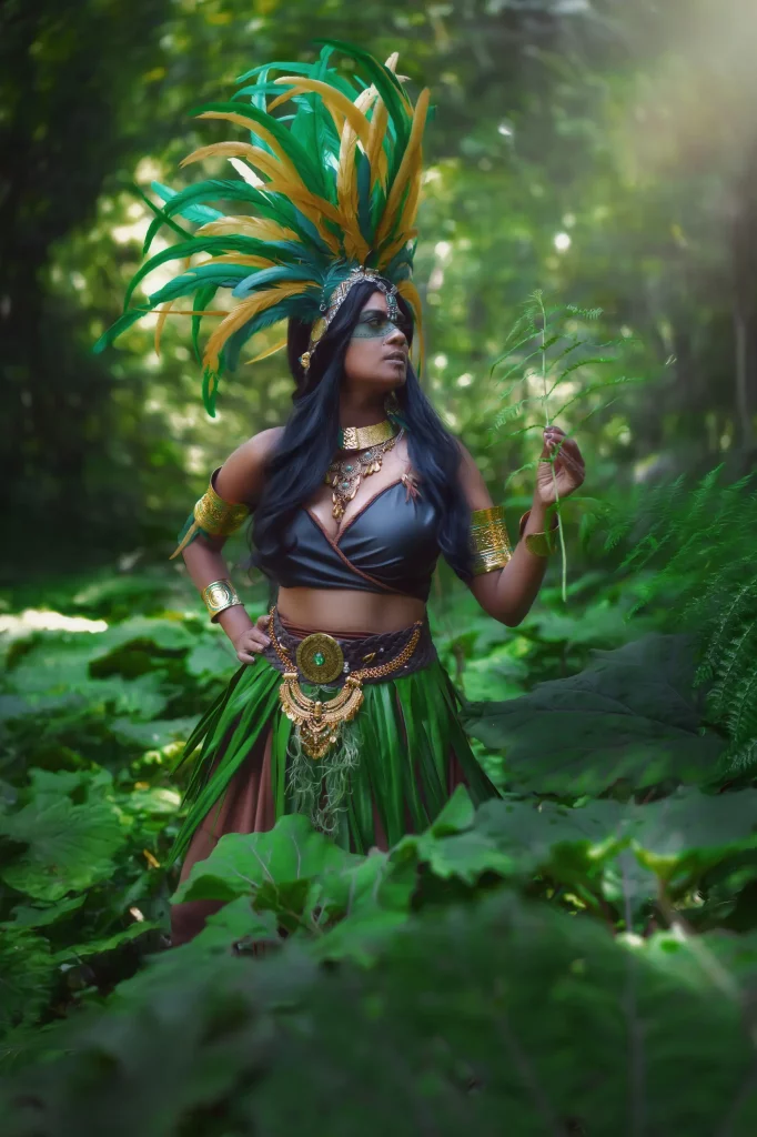 Azteca Warrior – Azteken-Kriegerin im Wald, hält ein Farnblatt in den Händen, Fantasy Fotoshooting in grüner Naturkulisse mit Sonnenstrahlen und mystischem Flair.