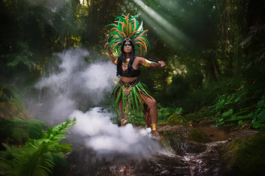 Azteca Warrior – Fantasy Fotoshooting einer Azteken-Kriegerin im Dschungel mit Federschmuck, goldenen Accessoires und mystischem Rauchnebel.