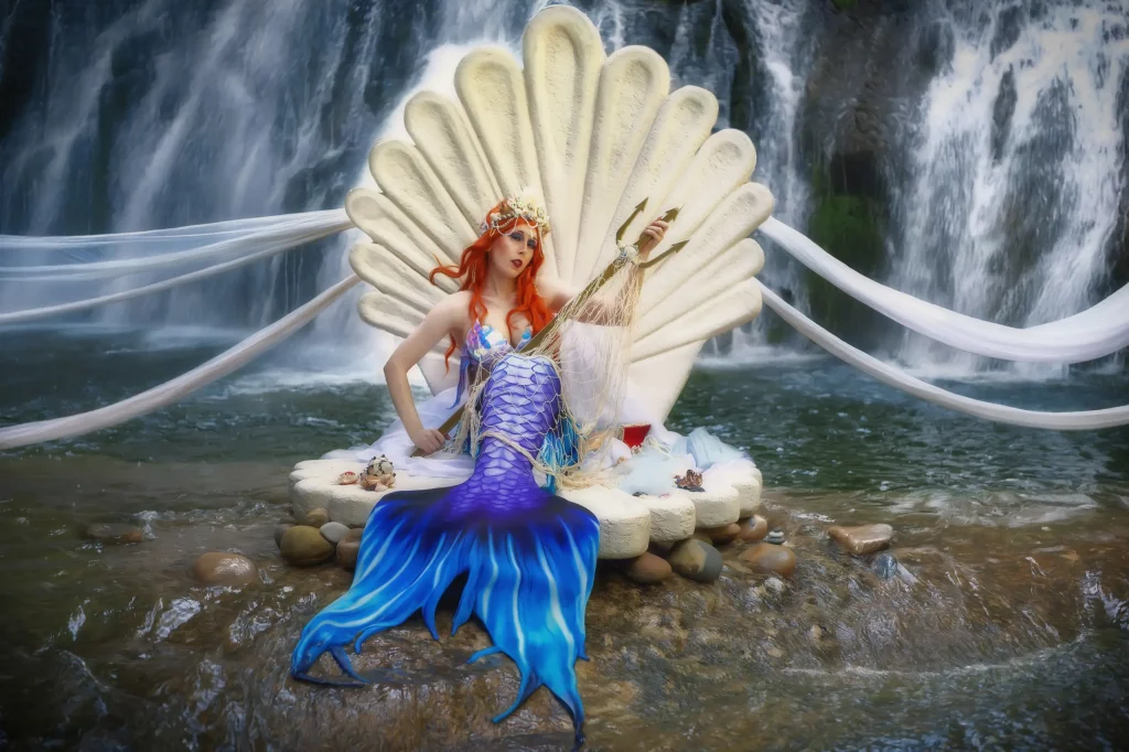Fantasy-Meerjungfrau auf Ocean Empress Muschel am Wasserfall mit schwebenden Tüllstoffen