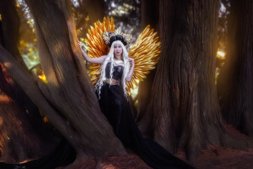 Verträumte Anime-Kriegerin mit goldenen Engelsflügeln und weißer Perücke zwischen alten Bäumen – magisches Fantasy Fotoshooting von Elena Frizler Photography in der Schweiz.