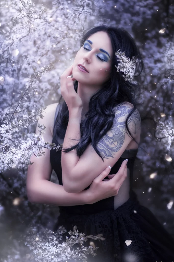 Verträumtes Fine Art Portrait mit Frau zwischen weissen Blüten und blauem Make up märchenhafte Fantasy Fotografie Schweiz