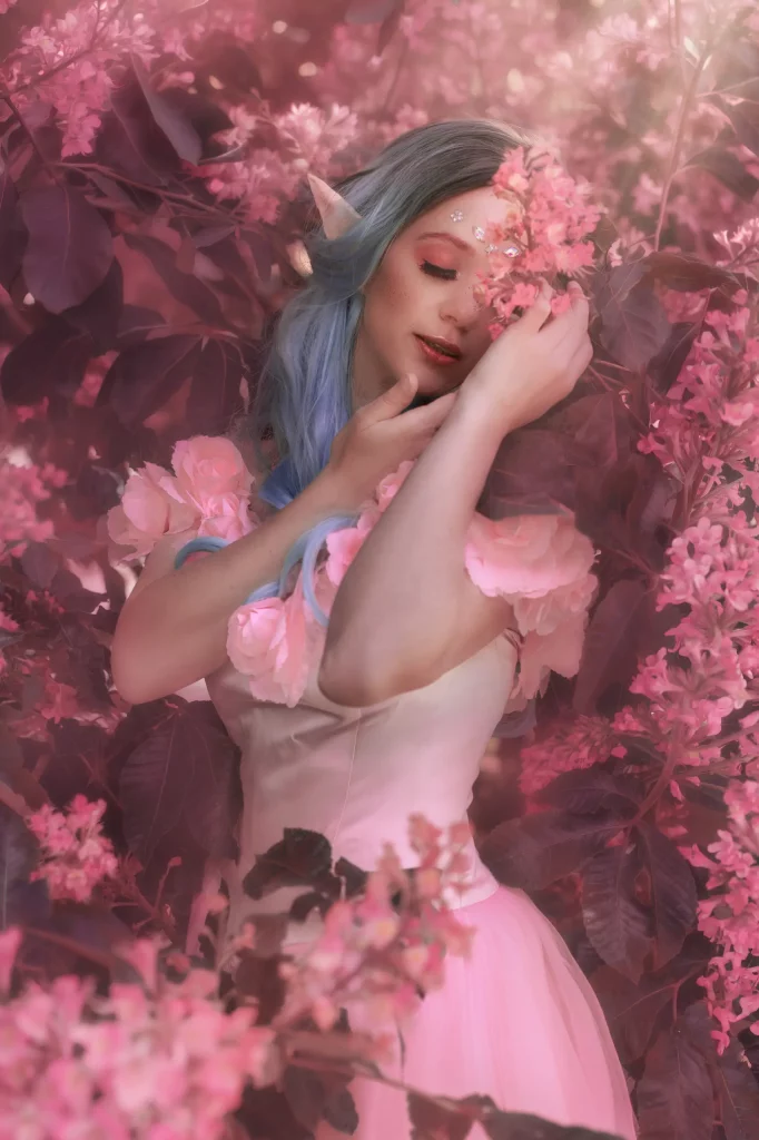 Cinematic Fantasy Elfe mit blauen Haaren zwischen rosa Blüten in verträumter Fine Art Atmosphäre