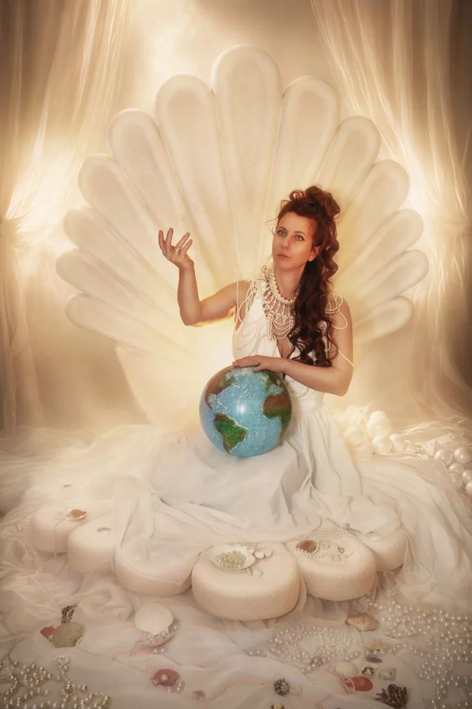 Frau im Venus-Reborn-Studio-Set mit Erdkugel auf Muschelthron als Symbol für Schöpfung und Neubeginn